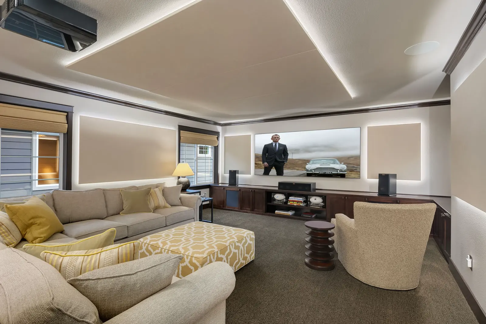 A home theater with LED backlit acoustic panels, Klipsch Atmos speakers, a projection screen and automated blackout shades